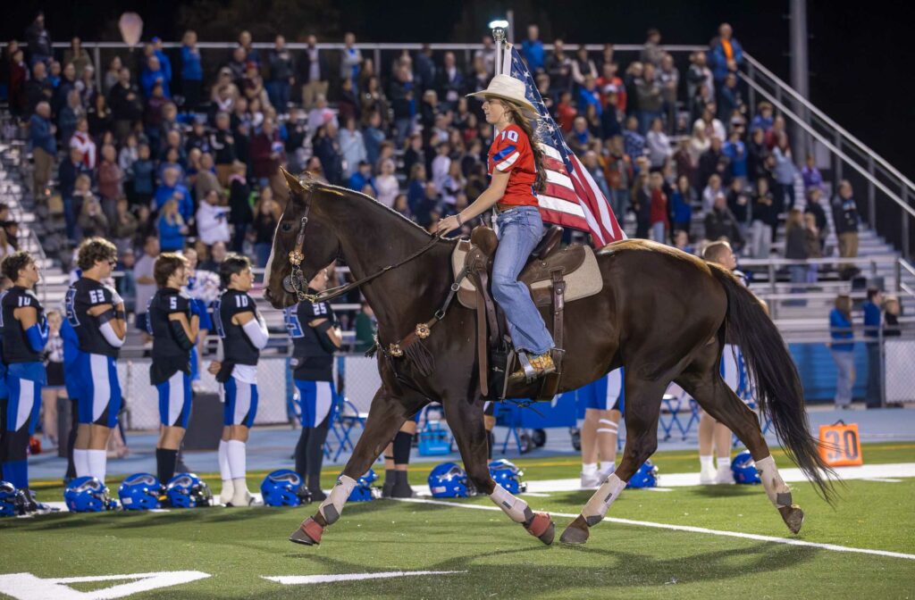 Coeur d'Alene vs Post Falls Varsity Football Homecoming - Woman riding a horse with the American Flag for the National Anthem.
